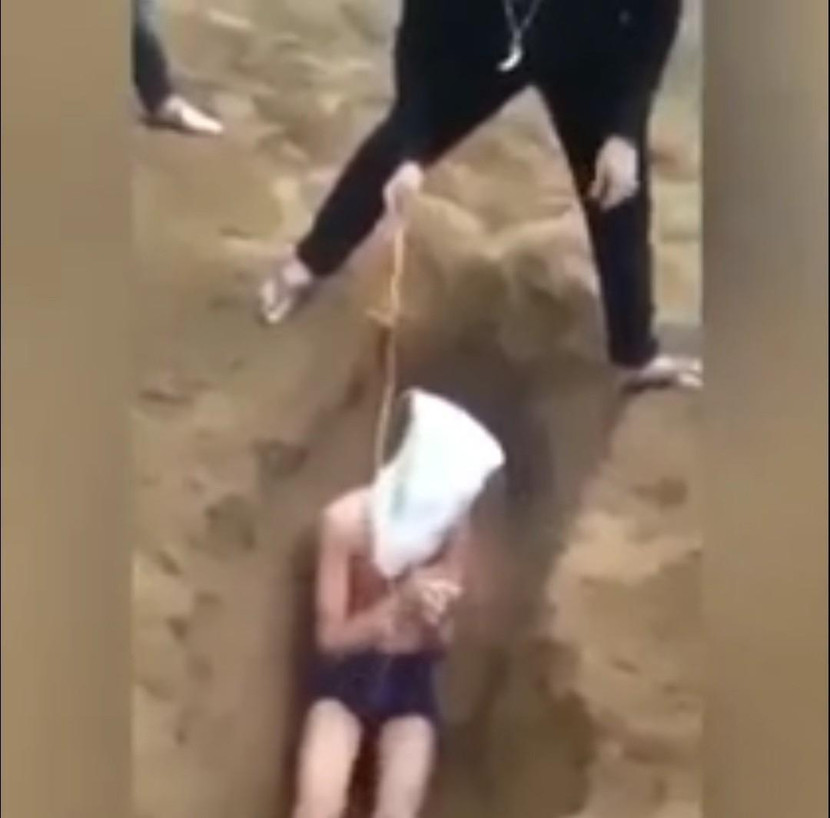 Trói tay, trùm đầu và vùi vào hố cát (ảnh cắt từ clip) Trói tay, trùm đầu và vùi vào hố cát (ảnh cắt từ clip)