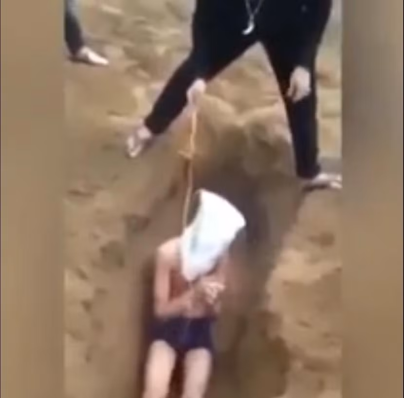 Trói tay, trùm đầu và vùi vào hố cát (ảnh cắt từ clip)