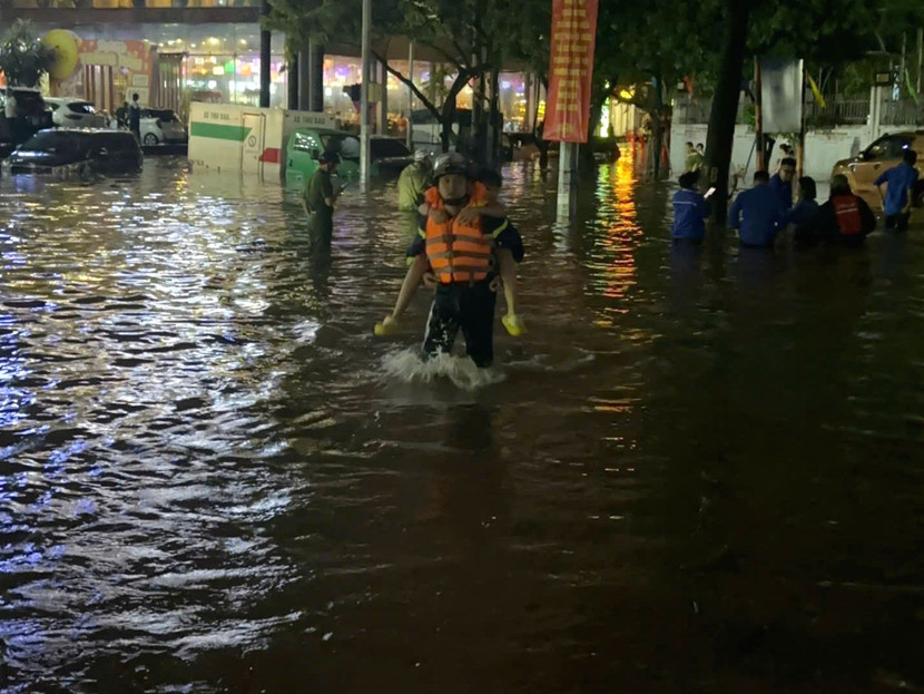 Hình ảnh cán bộ chiến sỹ Công an phường Ngọc Hà cõng các em học sinh ra khỏi khu vực sân ngập sâu của trường Tiểu học Nguyễn Bá Ngọc