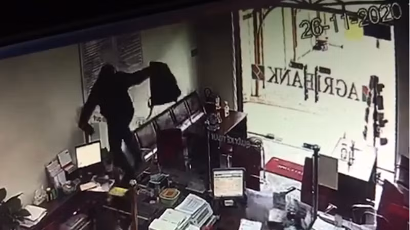 Hình ảnh đối tượng leo qua tấm kính ngăn giữa khách hàng và nhân viên ngân hàng để thực hiện ý đồ cướp tiền (Ảnh: Trích xuất camera) Hình ảnh đối tượng leo qua tấm kính ngăn giữa khách hàng và nhân viên ngân hàng để thực hiện ý đồ cướp tiền (Ảnh: Trích xuất camera)