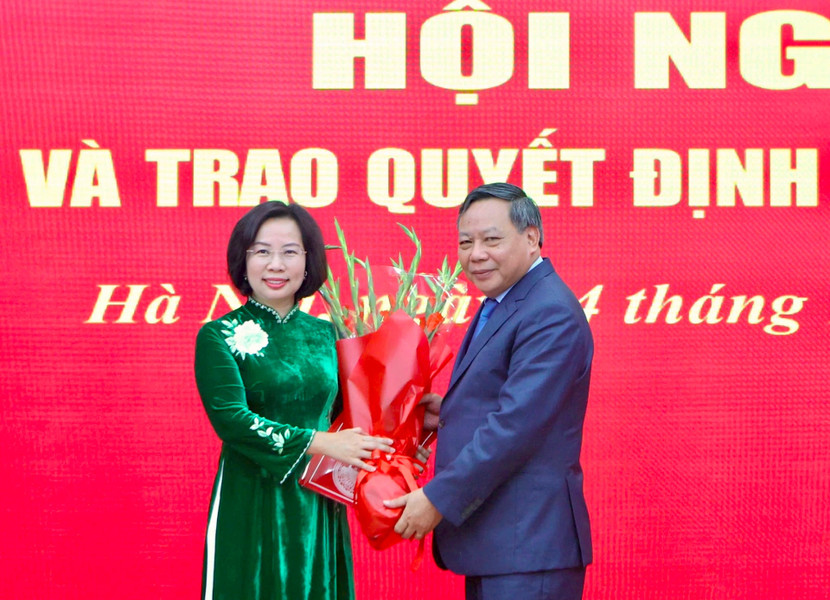 Phó Bí thư Thường trực Thành ủy Hà Nội Nguyễn Văn Phong trao quyết định và tặng hoa chúc mừng bà Bùi Huyền Mai.