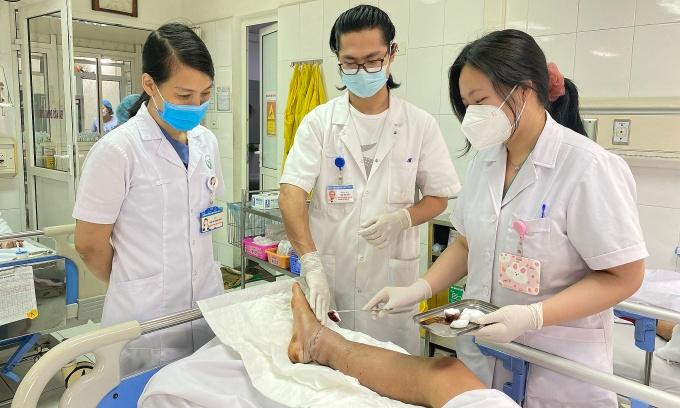 Bác sĩ chăm sóc vết thương sau khi nối thành công cẳng chân cho bệnh nhân