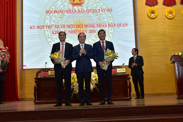 Phó Bí thư Thành ủy, Phó Chủ tịch Thường trực HĐND TP Nguyễn Ngọc Tuấn tặng hoa chức mừng tân Chủ tịch HĐND quận Tây Hồ Đỗ Anh Tuấn (phải) và tân Chủ tịch UBND quận Tây Hồ Nguyễn Đình Khuyến.