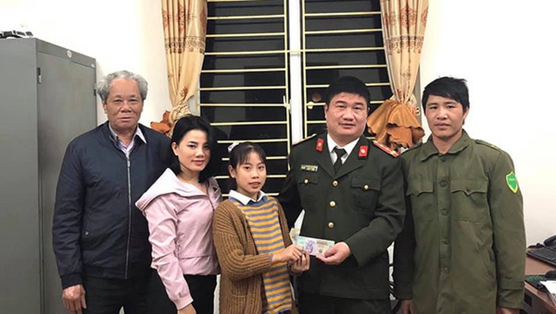 Hà trao lại chiếc túi và số tiền mình nhặt được cho công an xã để tìm người đánh rơi