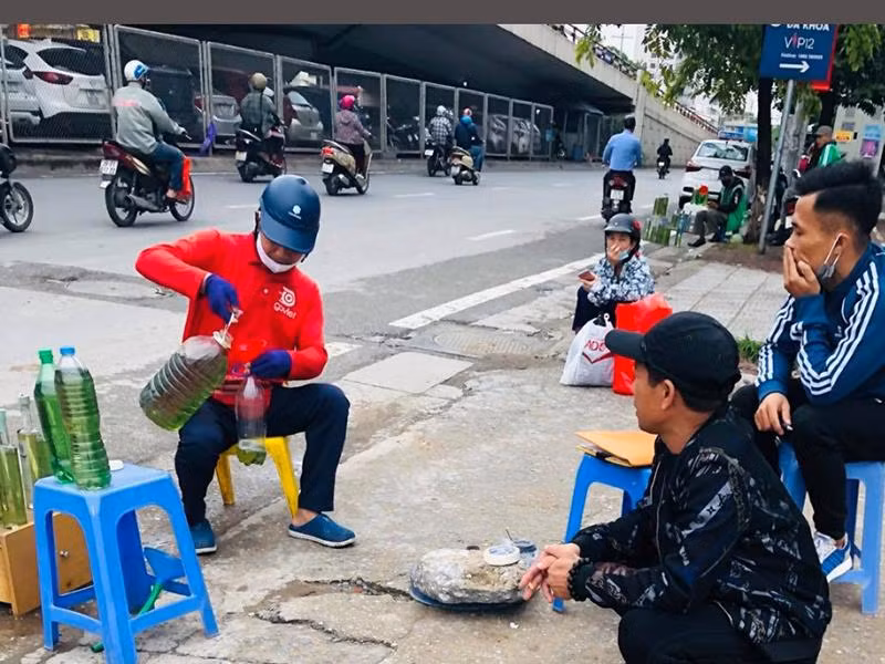Một người đang bán xăng và ngay bên cạnh có một người khác hút thuốc lá