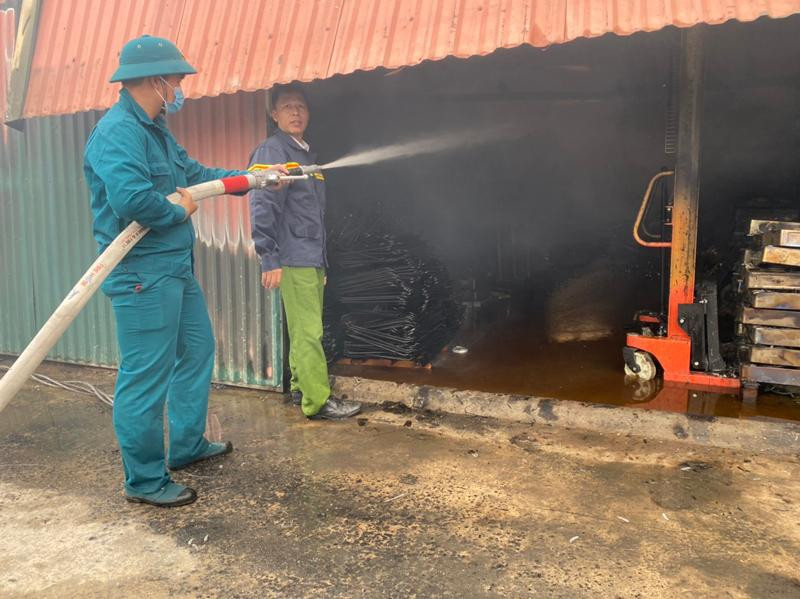 Lực lượng dân quân tự vệ phối hợp xử lý dập tàn, sau khi đám cháy đã được khống chế tại khu vực kho xưởng