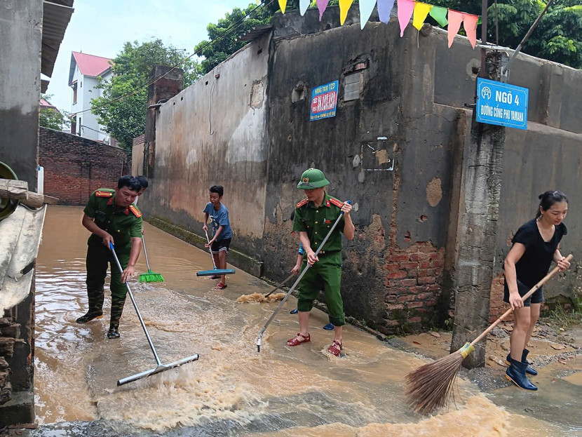 Lực lượng Công an và người dân xã Trung Giã dọn dẹp vệ sinh ngõ xóm sau khi nước rút
