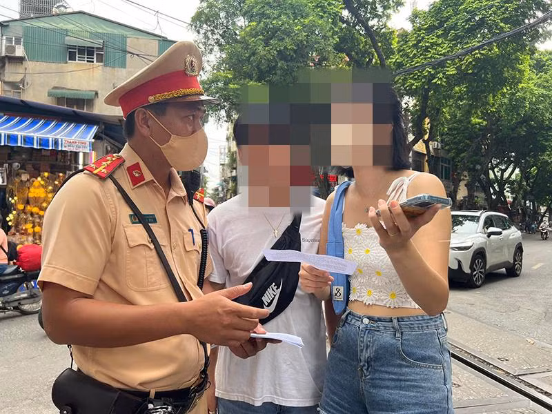 Phòng Cảnh sát giao thông - Công an thành phố Hà Nội phát tờ rơi song ngữ Anh - Việt tuyên truyền an toàn giao thông tại khu vực đường tàu Phùng Hưng