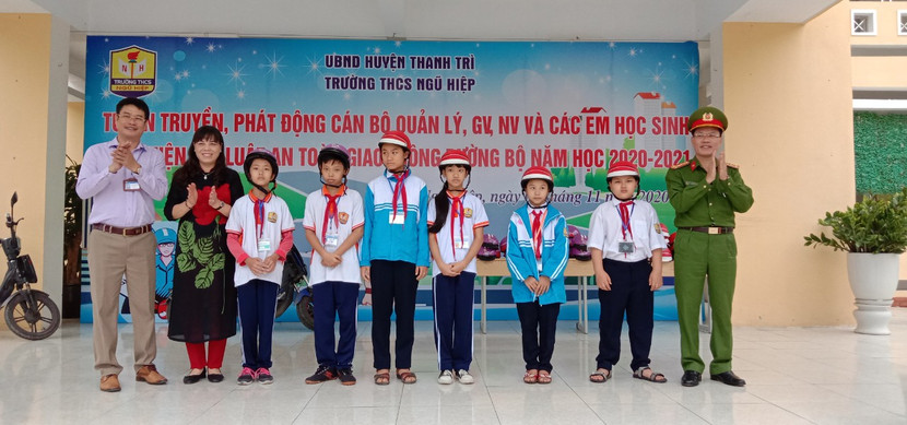 Thượng tá Nguyễn Mạnh Dầu, Trưởng CAH Thanh Trì và thầy Đặng Thanh Quang, Hiệu trưởng Trường THCS Ngũ Hiệp trao mũ bảo hiểm cho các em học sinh