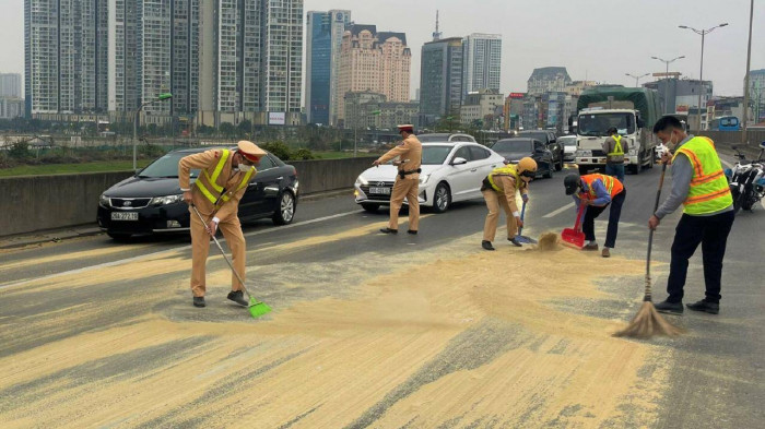 Cảnh sát giao thông thu dọn nhiều bao tải cám rơi trên đường Vành đai 3