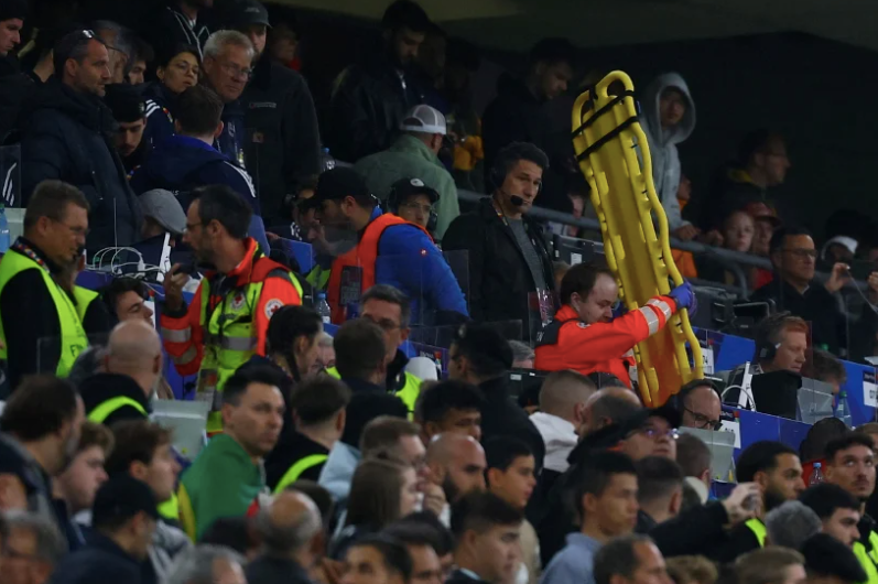 Các nhân viên y tế mang cáng vào khán đài sau sự cố với một khán giả trong trận đấu
