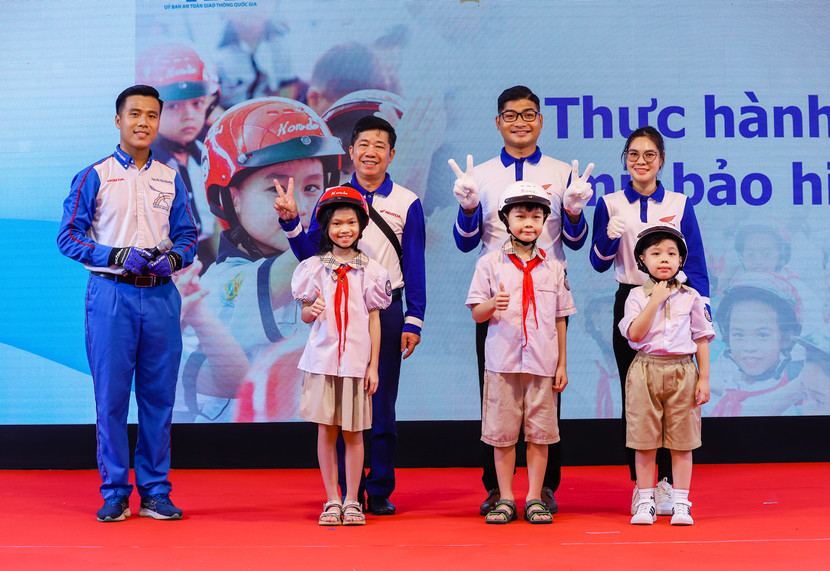 Các em học sinh thực hành đội mũ bảo hiểm đúng cách và an toàn