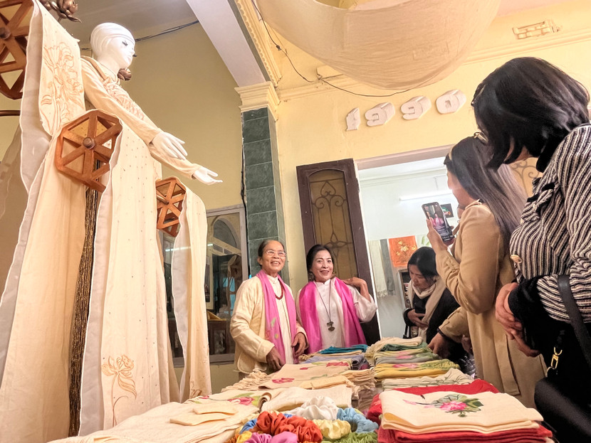 Nghệ nhân Phan Thị Thuận (bên trái) giới thiệu sản phẩm với đối tác, du khách