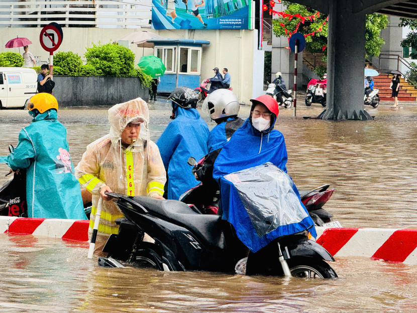 Dầm mình trong mưa, nhưng chiến sĩ Cảnh sát giao thông vẫn nỗ lực giúp người dân qua điểm ngập an toàn