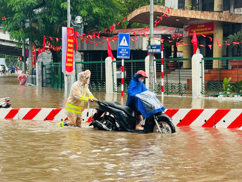 Chiến sĩ Cảnh sát giao thông giúp người dân qua nơi ngập úng an toàn