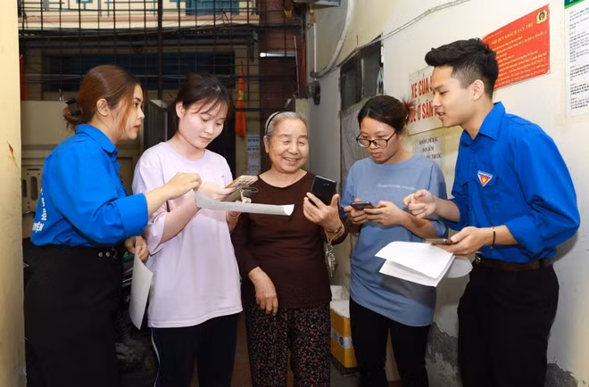 Những sinh viên tình nguyện của trường Đại học Lao động xã hội đồng hành cùng Công an phường Trung Hòa đến từng hộ dân hướng dẫn cài đặt VNeID
