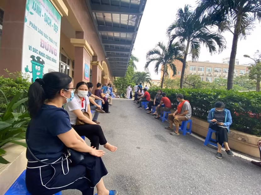 Người dân ngồi chờ tiêm vaccine Covid-19 tại Bệnh viện E Người dân ngồi chờ tiêm vaccine Covid-19 tại Bệnh viện E