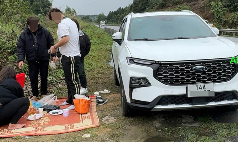 Hình ảnh ghi lại một gia đình dừng bên lề đường cao tốc trải chiếu ăn cơm trưa
