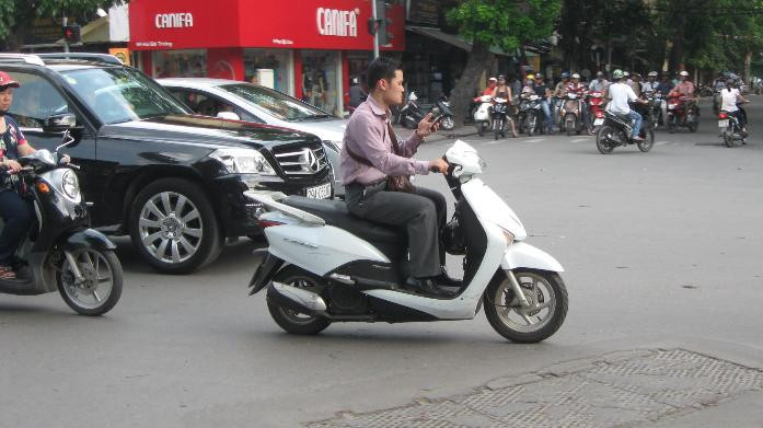 Không đội mũ bảo hiểm, vừa đi vừa dùng điện thoại