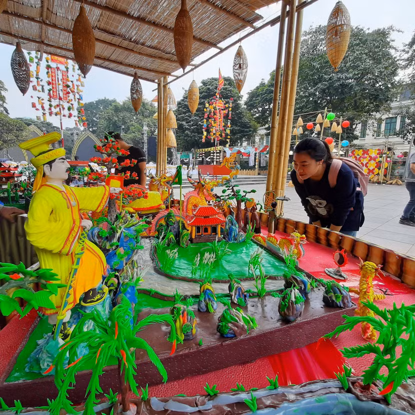 Một bạn trẻ đang chăm chú xem tiểu cảnh về lịch sử Hà Nội do các nghệ nhân làng nghề tò he Xuân La thực hiện