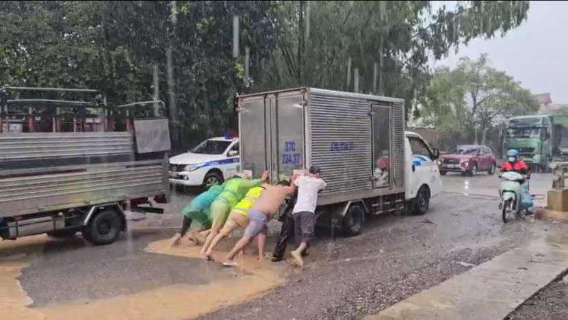 Các chiến sĩ Cảnh sát giao thông cùng người dân đẩy xe tải chết máy qua đoạn ngập Các chiến sĩ Cảnh sát giao thông cùng người dân đẩy xe tải chết máy qua đoạn ngập