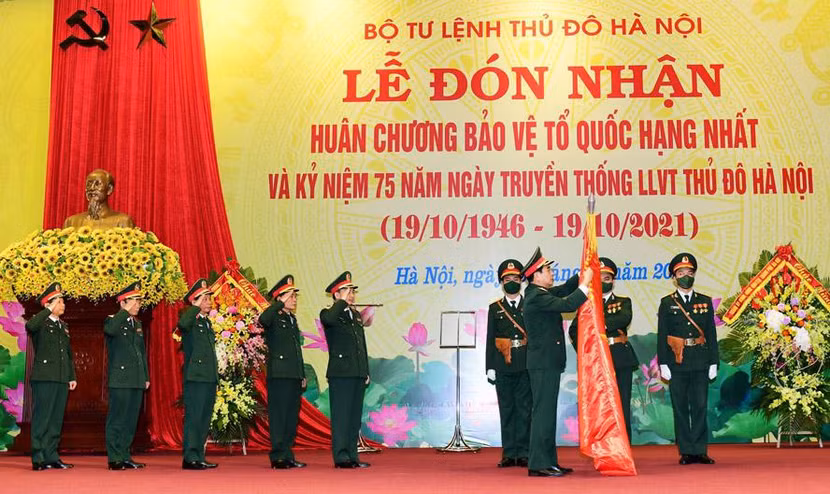 Đại tướng Phan Văn Giang - Ủy viên Bộ Chính trị, Bộ trưởng Bộ Quốc phòng gắn Huân chương Bảo vệ Tổ quốc hạng Nhất lên lá cờ truyền thống của lực lượng vũ trang Thủ đô