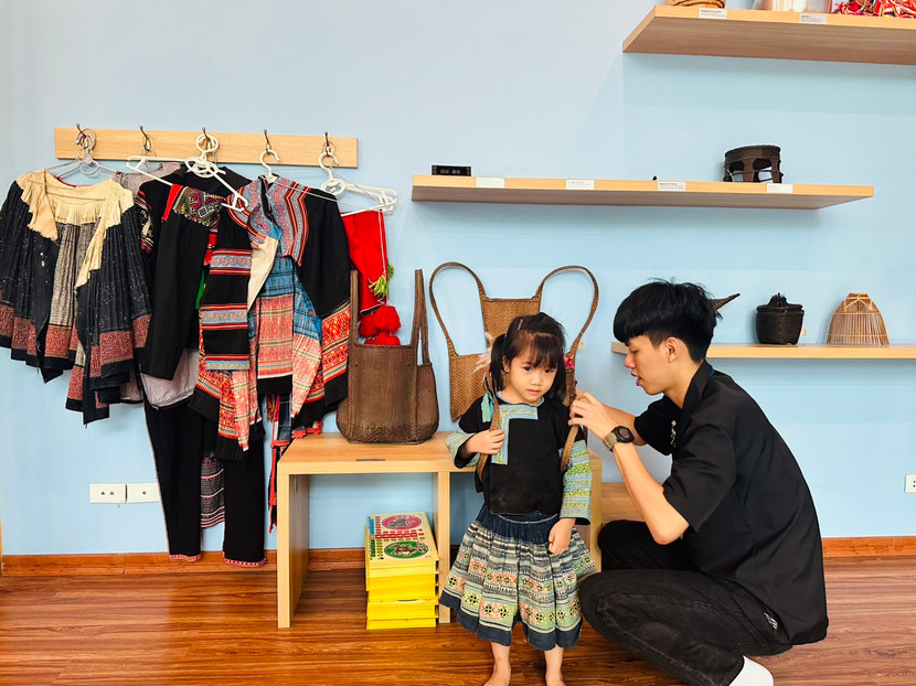 Em nhỏ thử mặc trang phục dân tộc Mông.
