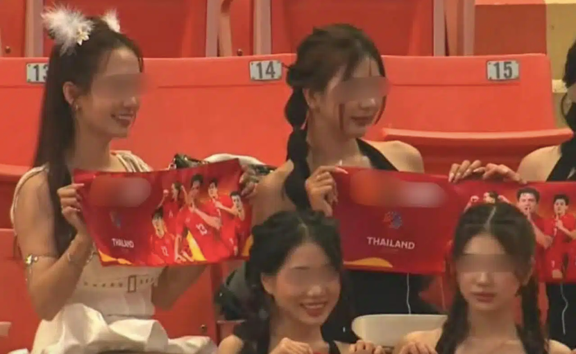 Nhóm nữ khán giả mang theo biểu ngữ có hình ảnh U22 Việt Nam và tên một trang web cờ bạc (đã được che) xuất hiện trên sân Rajamangala trong ngày khai màn môn bóng đá nam SEA Games 33 hôm 3-12 (Ảnh: Daily News)