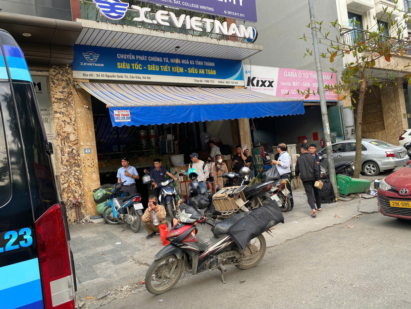 Hành khách cùng lỉnh kỉnh hàng hóa chờ xe ngay trước cửa văn phòng nhà xe X.E Việt Nam