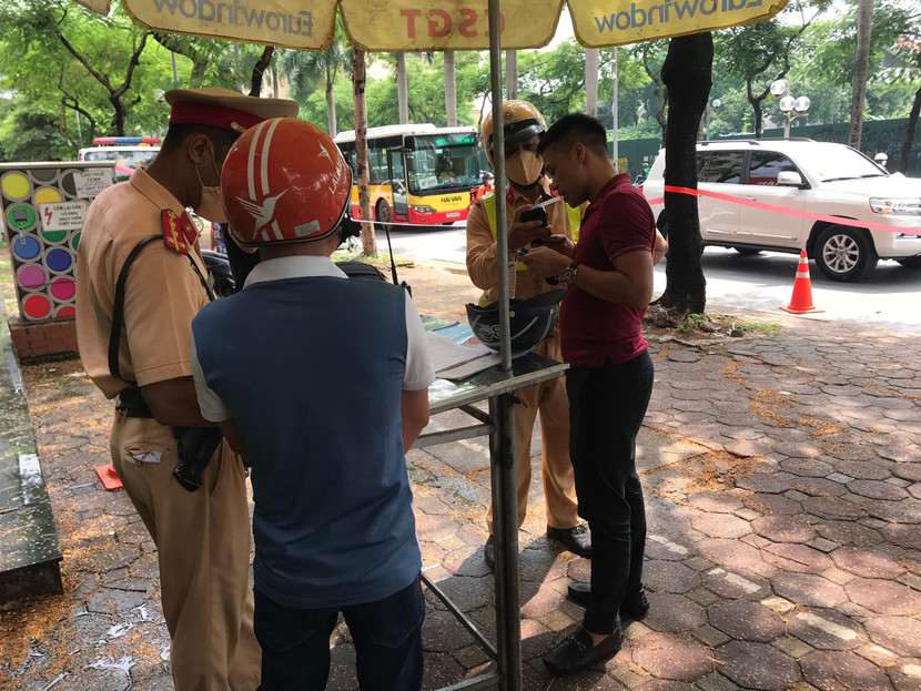 Người đàn ông áo đỏ đang được cán bộ chiến sĩ đo nồng độ cồn