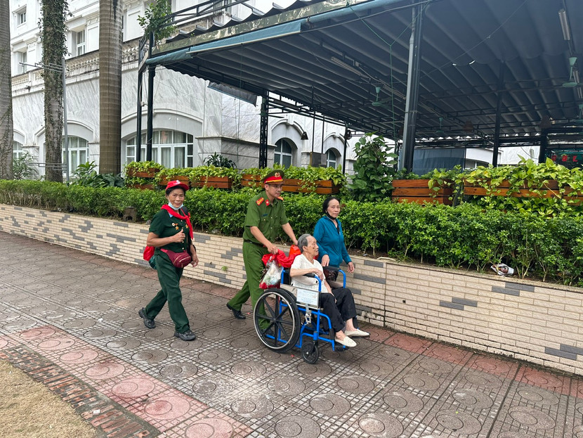 Trung tá Trần Văn Cường - Trưởng CAP Ba Đình hỗ trợ đưa một cụ bà 101 tuổi vào khu vực chỗ ngồi ưu tiên xem diễu binh