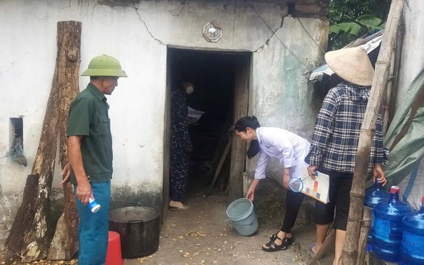 Cán bộ y tế xã Hòa Lâm (huyện Ứng Hòa) hướng dẫn người dân vệ sinh môi trường sau nước rút tại một hộ gia đình