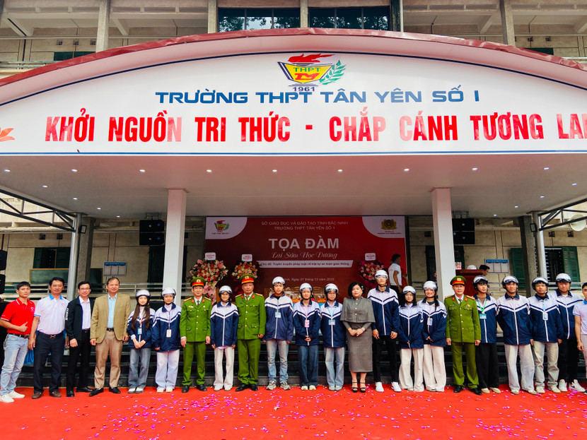 Đại diện Ban Tổ chức trao tặng mũ bảo hiểm và hướng dẫn cách đội mũ đúng quy cách cho học sinh