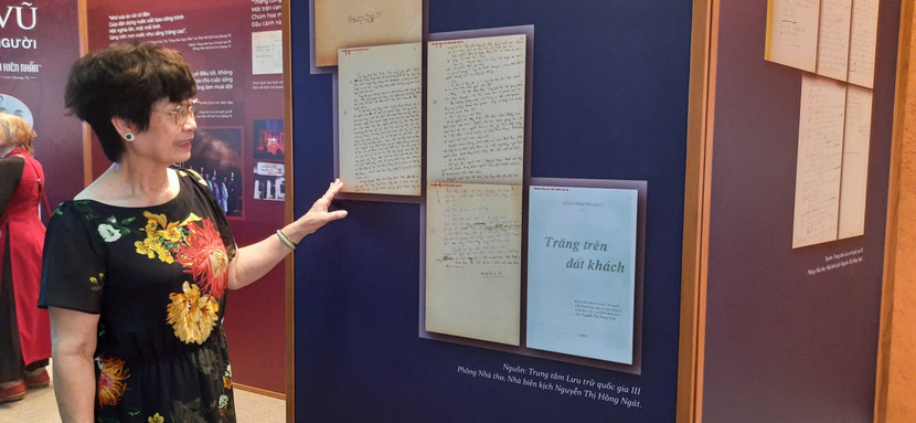 Nhà biên kịch Nguyễn Thị Hồng Ngát bên tài liệu trưng bày tại triển lãm - kịch bản "Trăng trên đất khách" do tác giả viết tay.