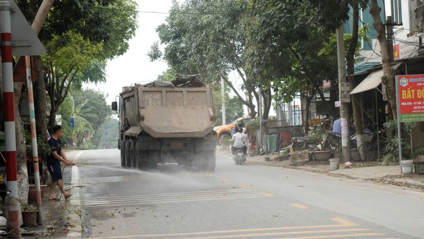Mỗi lần xe đi qua, người dân phải phun nước cho đỡ bụi