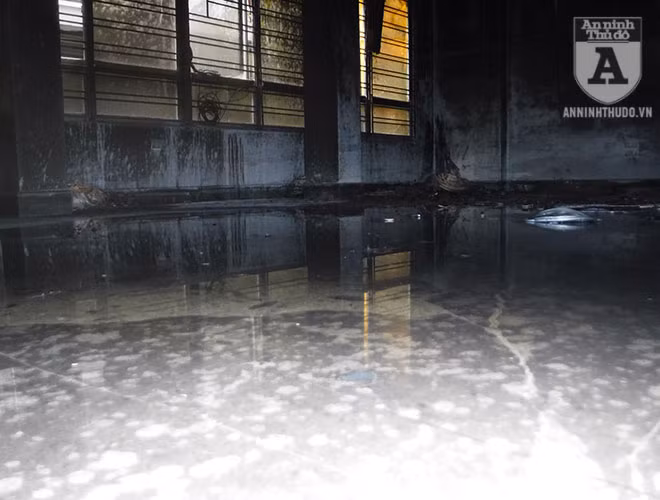 Nước chữa cháy loang loáng trên nền nhà, trở nên đen vì nhiều tro bụi