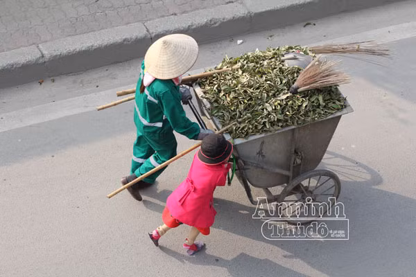 Xúc động hình ảnh em bé đi quét rác cùng mẹ trong ngày Tết ảnh 1