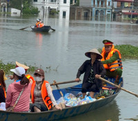 Dùng thuyền tiếp tế thực phẩm cho người dân bị cô lập do mưa bão gây ngập úng ở giáo xứ Đồng Chiêm