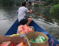 Dùng thuyền tiếp tế thực phẩm cho người dân bị cô lập do mưa bão gây ngập úng ở giáo xứ Đồng Chiêm