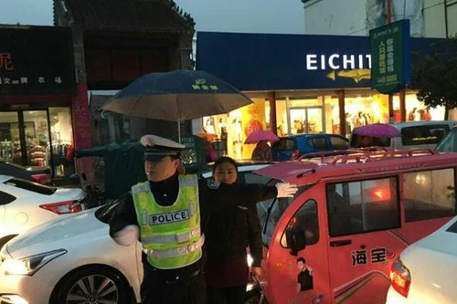 Hình ảnh đẹp về người phụ nữ che mưa cho cảnh sát giao thông 