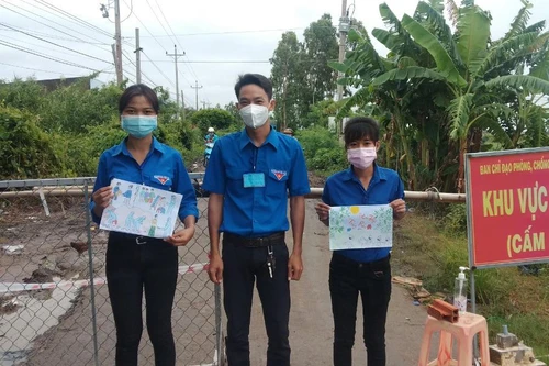 Hai nữ tình nguyện viên trẻ vừa trực chốt kiểm soát dịch vừa vẽ tranh cổ động
