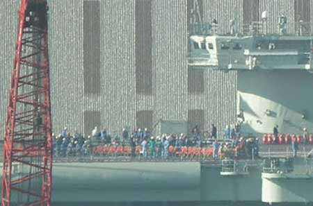 Boong tàu sân bay Liêu Ninh đang được chuẩn bị cho một buổi lễ gì đó, hình ảnh có độ phân giải không cao. Một số thiết bị phục vụ cho hội nghị ngoài trời đang được lắp đặt. Các nhân viên đang khẩn trương lắp đặt thiết bị phục vụ cho buổi lễ, còn buổi lễ gì thì còn phải chờ. Phần mũi tàu sân bay đầu tiên của Trung Quốc nhìn từ phía bên kia cầu cảng Đại Liên. Tàu sân bay được sơn số hiệu 16, trên boong tàu có 2 trực một trong 2 chiếc có vẻ là trực thăng không người lái mới. Ghế ngồi phục vụ cho khách mời đã được sắp sẵn trên boong tàu sân bay. Một lối đi có mái che đã được lắp đặt từ cầu cảng lên boong tàu, điều đó cho thấy đây là một buổi lễ quan trọng có sự chứng kiến của các quan chức cấp cao Trung Quốc.