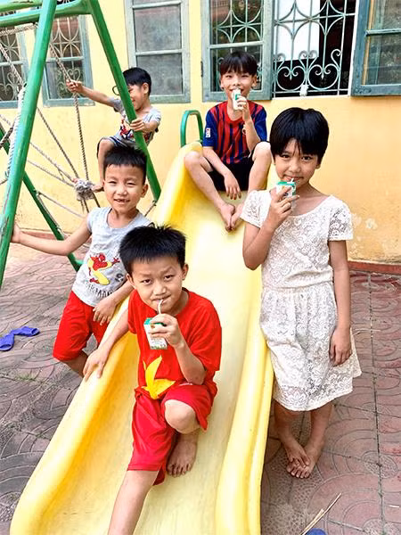 Em Lan Thương (áo đầm trắng) cùng các bạn quây quần uống sữa bên chiếc xích đu trong trung tâm