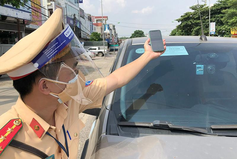 Cán bộ tổ công tác Đội CSGT số 12 check mã QR đối với xe "luồng xanh" được cấp mã lưu thông trong thời gian giãn cách xã hội