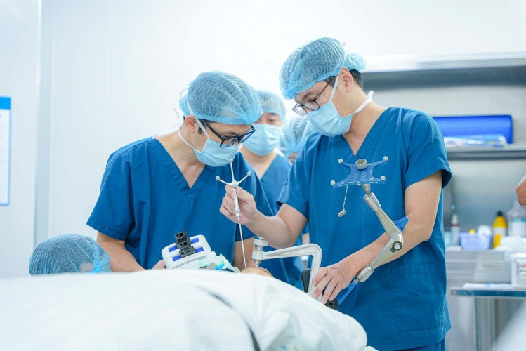 Đội ngũ bác sĩ cài đặt cánh tay Robot AutoGuide trước khi tiến hành đưa điện cực vào nội sọ. Đội ngũ bác sĩ cài đặt cánh tay Robot AutoGuide trước khi tiến hành đưa điện cực vào nội sọ.