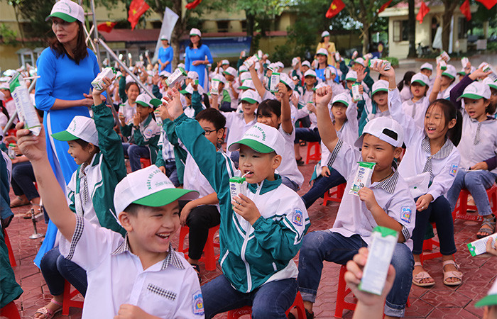 Các em học sinh Trường tiểu học A hào hứng tham gia hoạt động uống sữa cùng các bạn tại sân trường trong buổi lễ phát động
