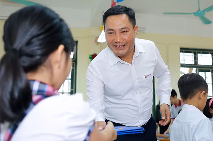 Ông Lê Ánh Dương - Phó Tổng Giám đốc EVNHANOI đến tận lớp, trao tận tay những cuốn vở cho các em học sinh.
