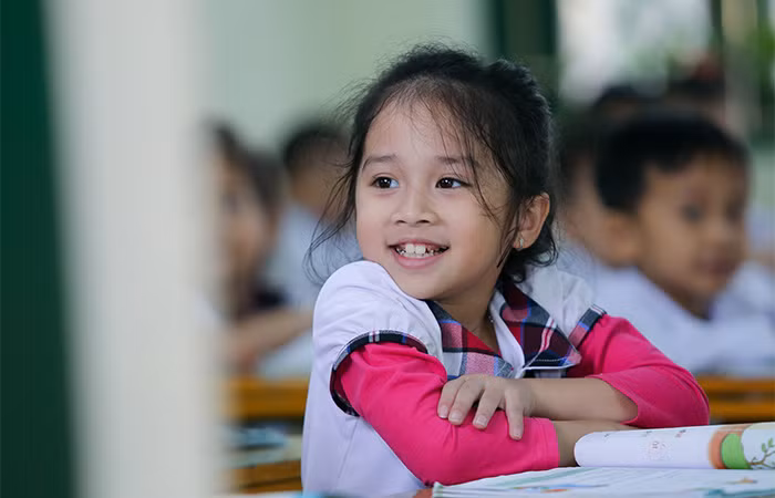 Một em học sinh trong lớp 1 ngồi ngay ngắn để nhận quà