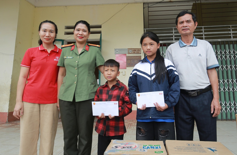 Trung tá Đỗ Thị Vân Quế thay mặt Tòa soạn An ninh Thủ đô trao 2 trong số 10 phần quà bằng tiền mặt tới hai em Lý Thị Dùa và Lý Thanh Chiêu, mồ côi cha sau đợt lũ quét