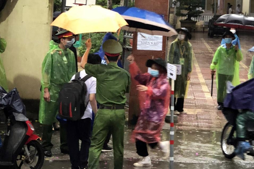 Công an huyện Hoài Đức che mưa giúp thí sinh vào điểm thi sáng 12-6